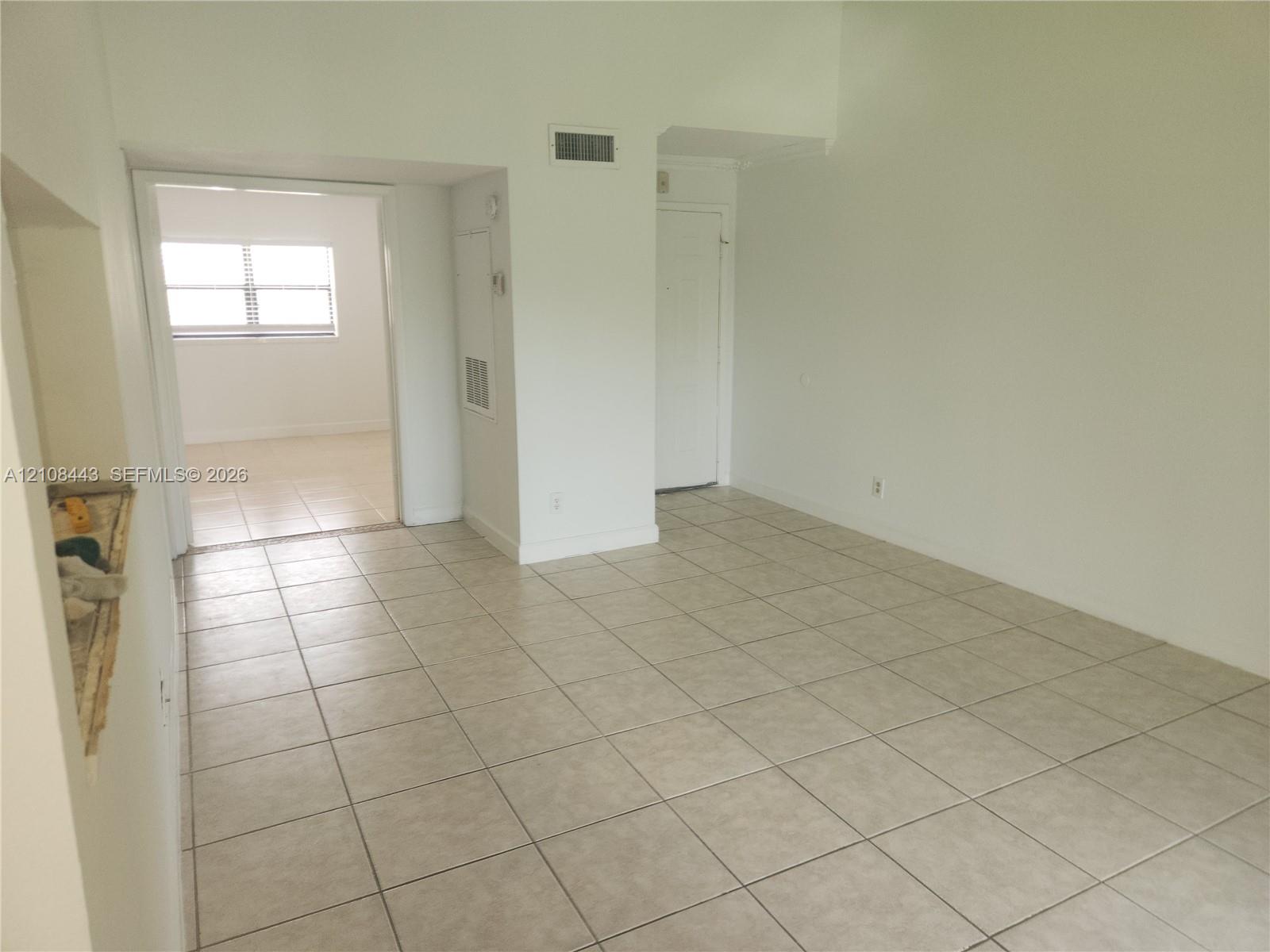 Neutral tile flooring, expansive wall space, and multiple interior openings with white-finish trim Neutral tile flooring, expansive wall space, and multiple interior openings with white-finish trim