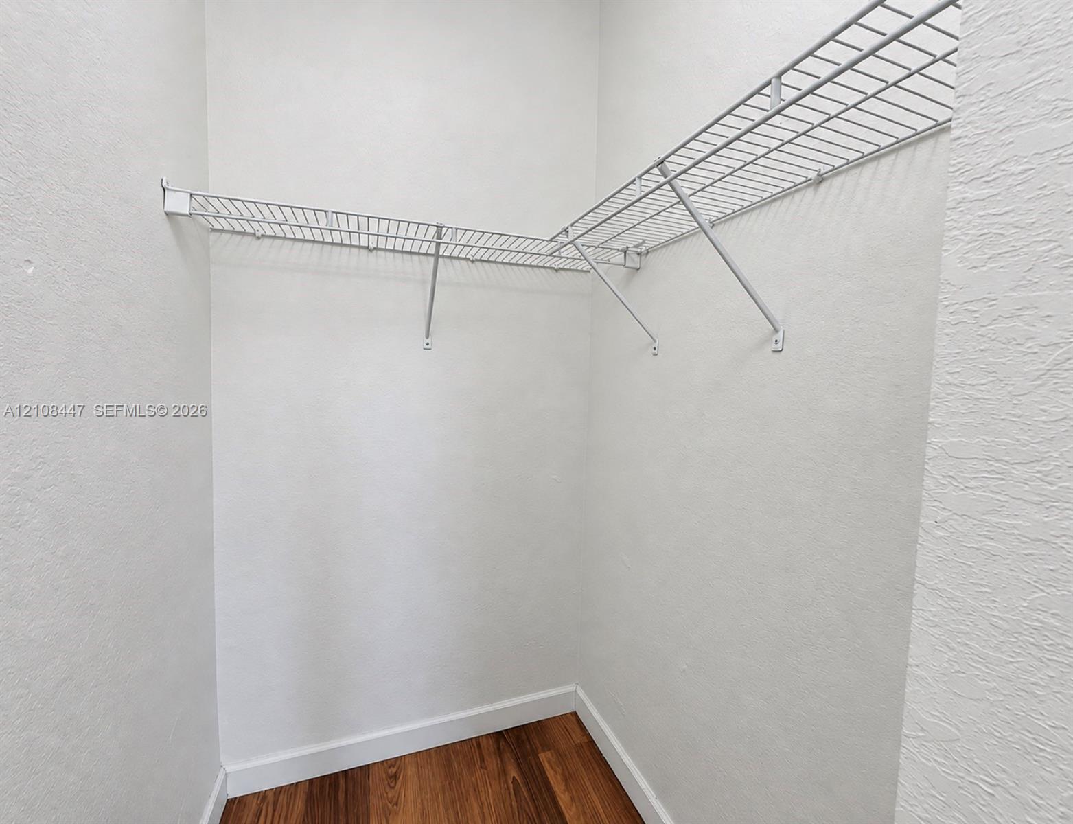 Storage space featuring white wire shelving and wood-finish flooring
