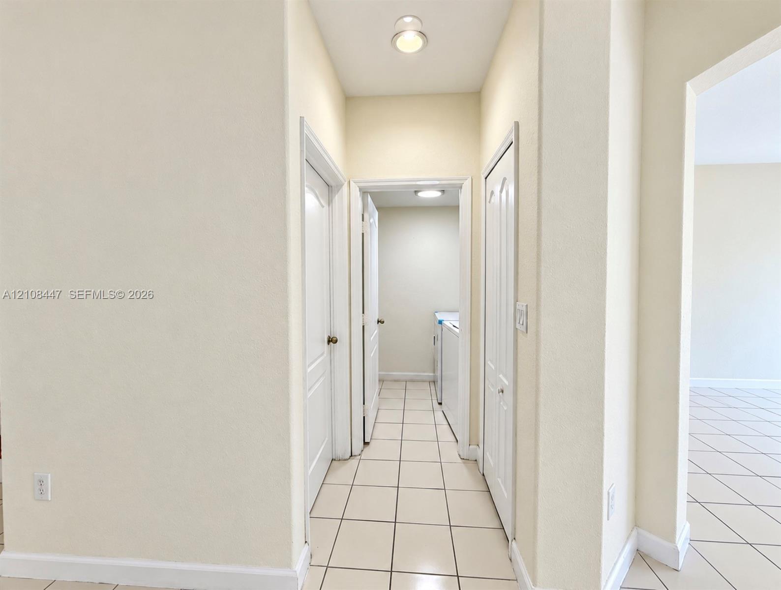 Neutral-toned interior hallway featuring ceramic tile flooring, multi-panel doors, and recessed lighting