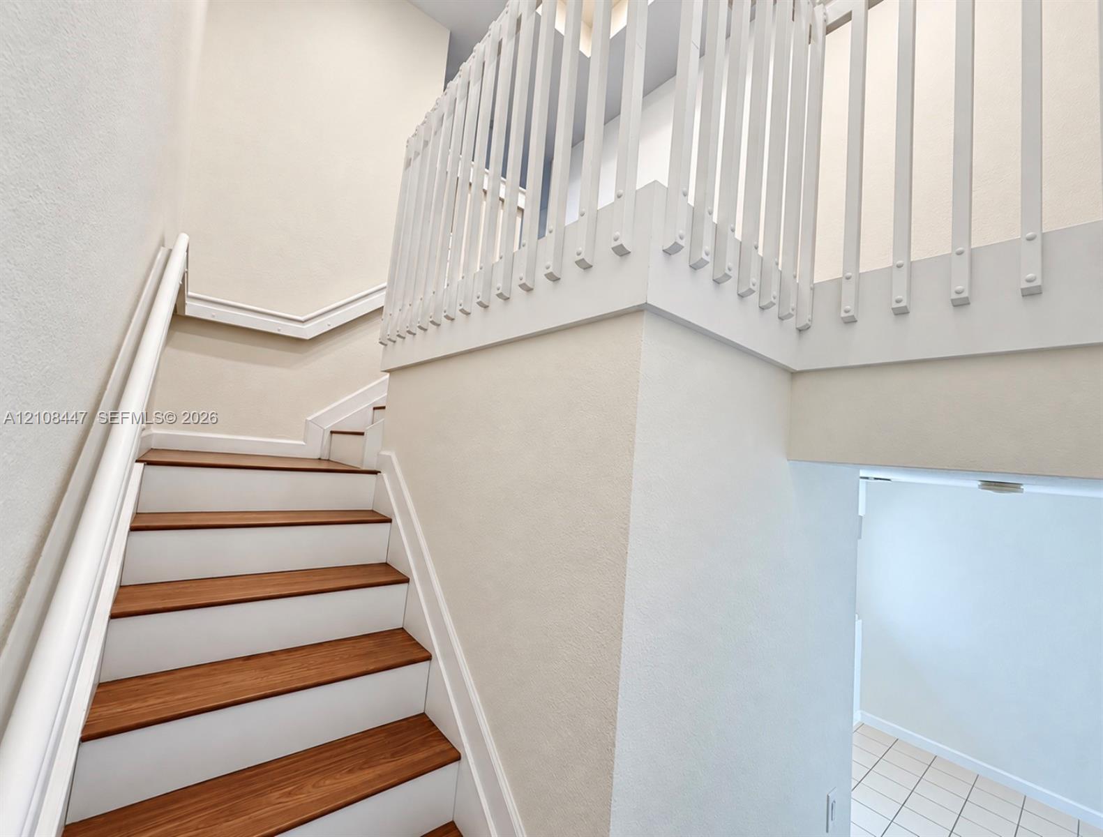 Staircase featuring wood-finish treads, white risers, and a white balustrade with a matching handrail