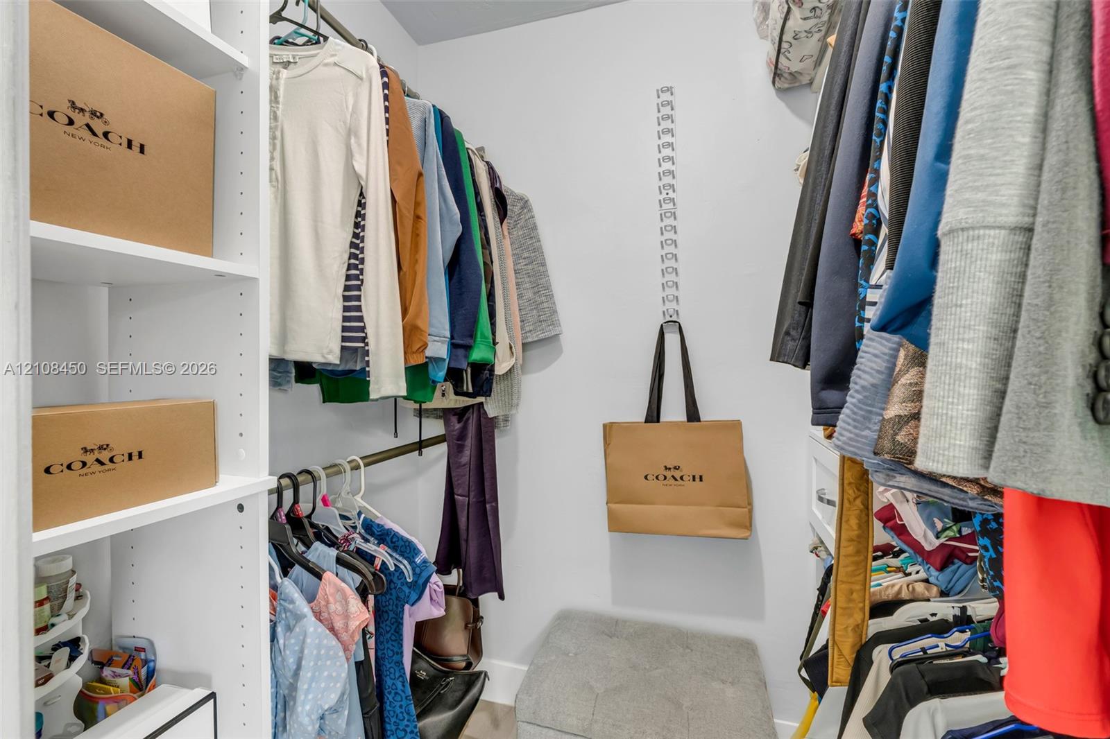 Walk-in closet featuring white built-in shelving and multi-level metal hanging rods