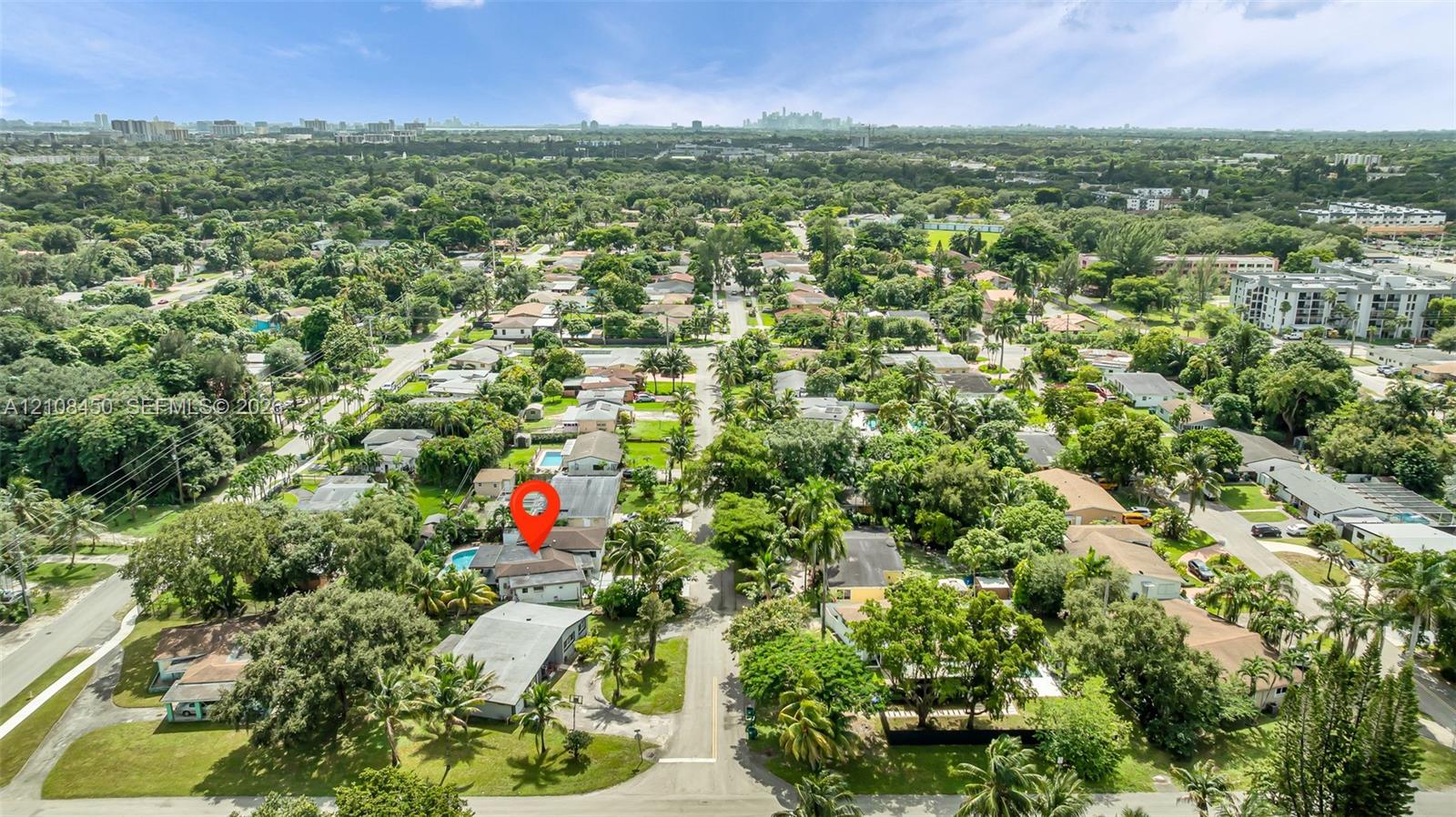 Aerial perspective featuring mature tree-lined streets, established residential landscaping, and a rear swimming pool