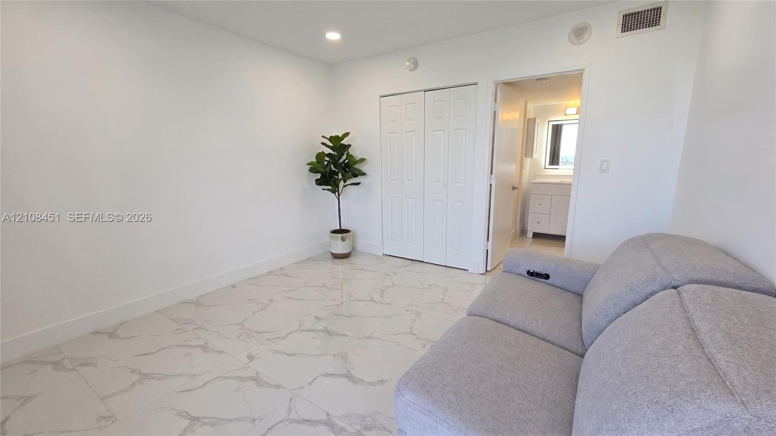 Interior space featuring large-format veined tile flooring, recessed lighting, and double-door closet cabinetry
