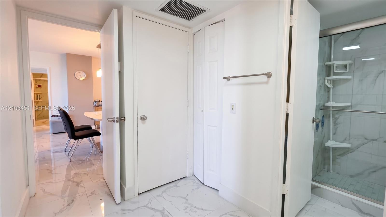 Walk-in shower with stone-finish wall tile, polished tile flooring, and multi-panel closet doors