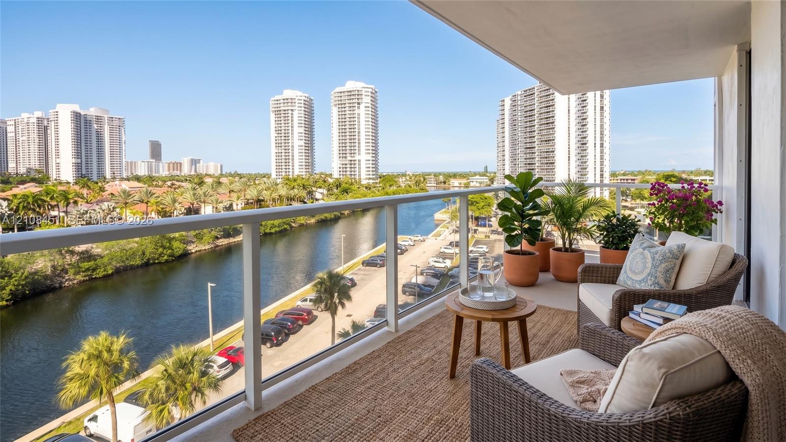 Covered balcony featuring glass railing and concrete flooring with water and urban skyline backdrop
