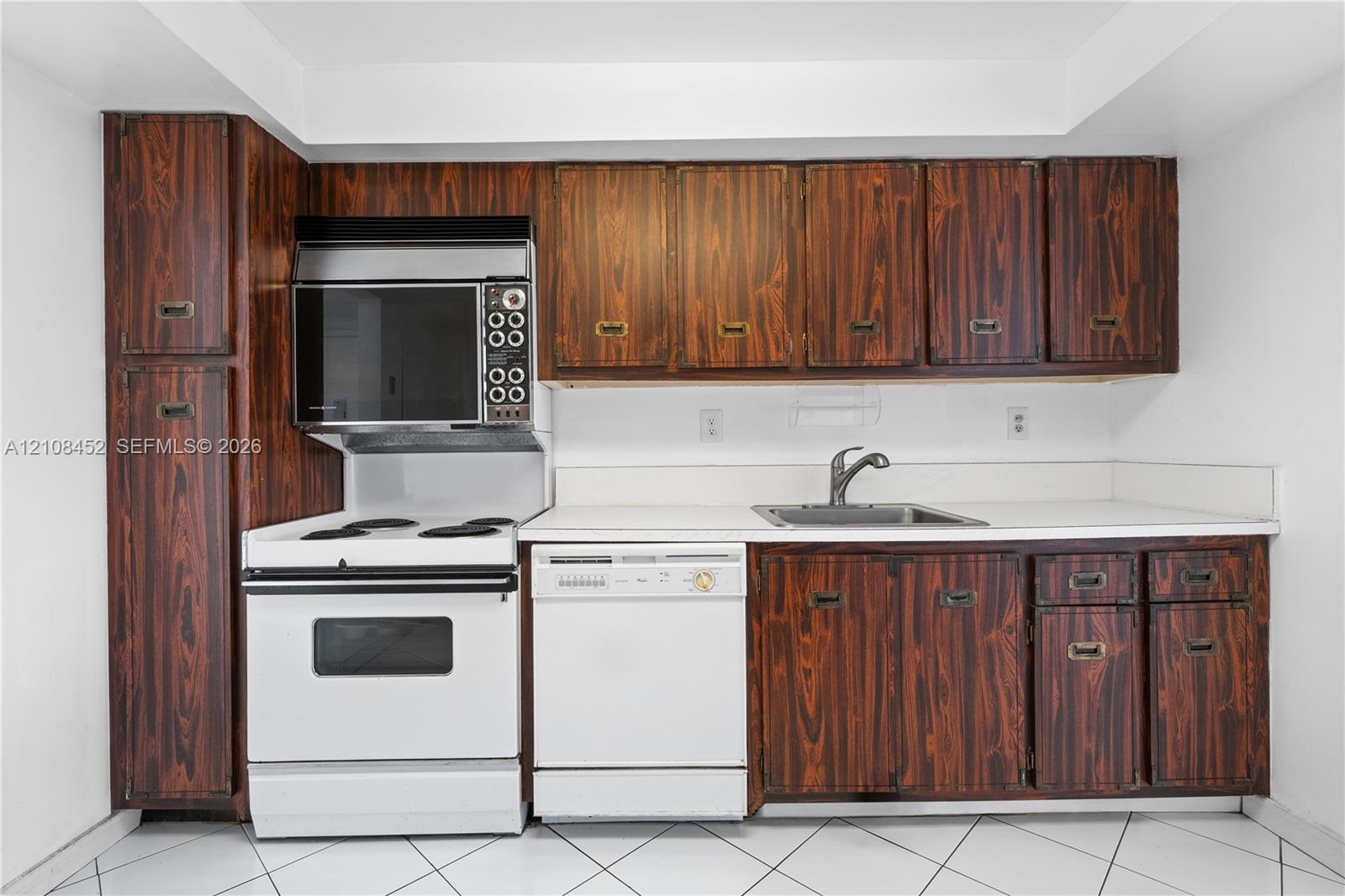 Kitchen featuring wood-grain cabinetry, solid surface countertops, white electric range with built-in microwave, integrated dishwasher, and stainless steel sink