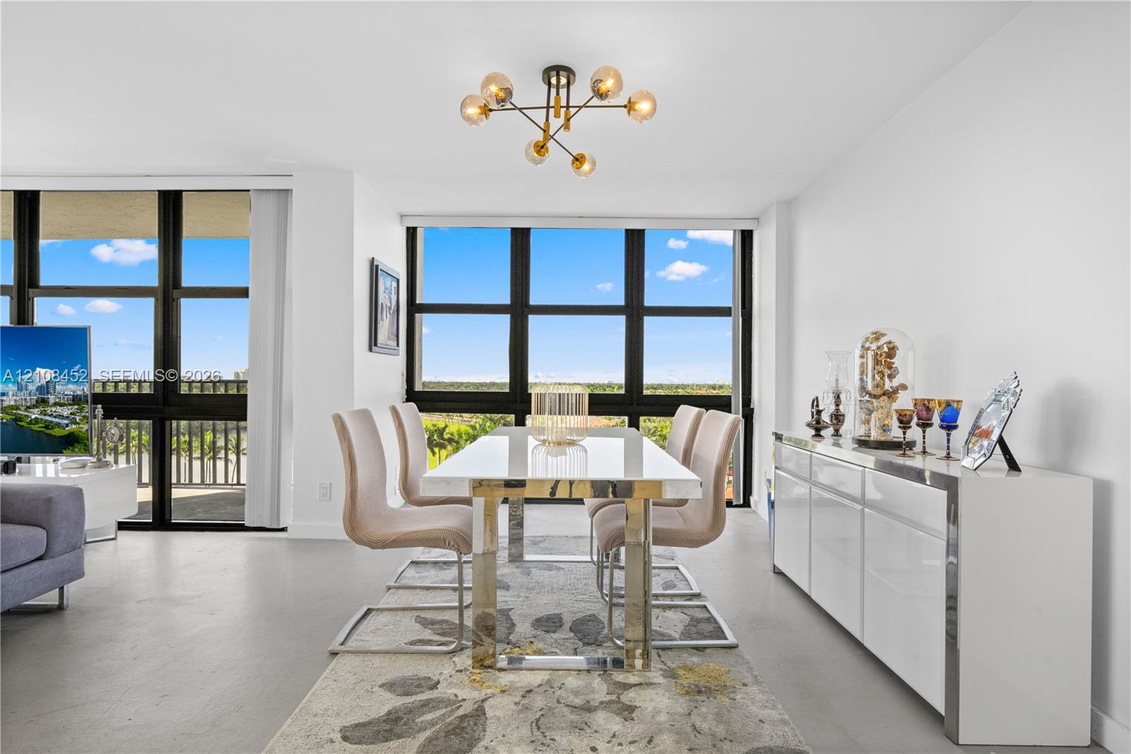 Dining area featuring floor-to-ceiling windows with black framing, polished concrete flooring, and a multi-arm, modern sphere chandelier