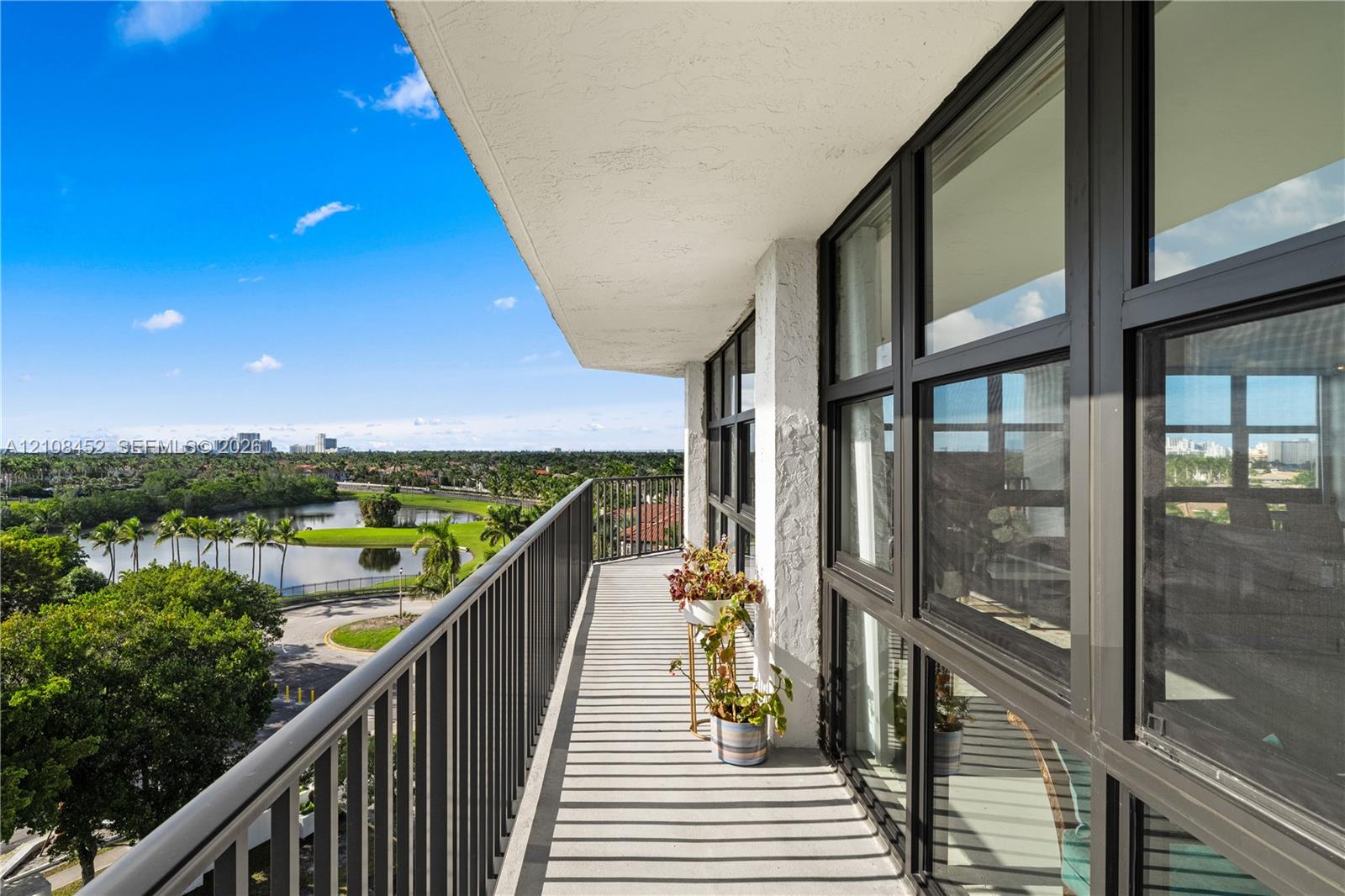 Covered balcony featuring black metal railings, floor-to-ceiling windows with dark framing, and textured exterior wall finish