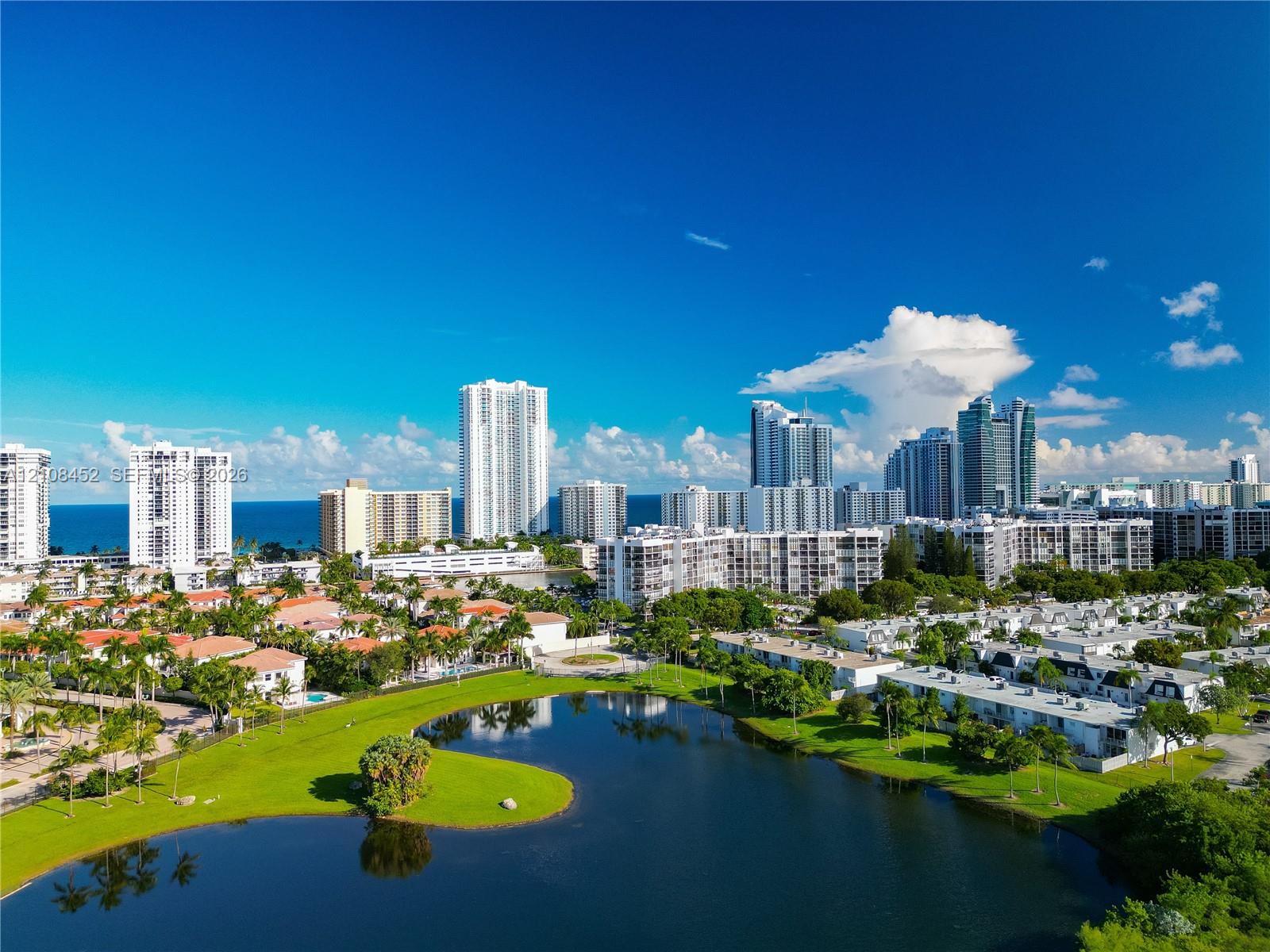 Aerial perspective featuring a central freshwater lake, manicured green space, mature palm trees, and surrounding coastal cityscape Aerial perspective featuring a central freshwater lake, manicured green space, mature palm trees, and surrounding coastal cityscape