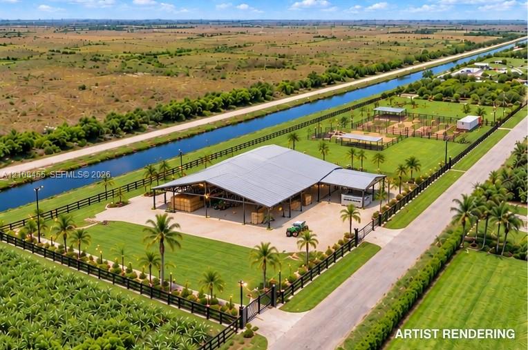 Expansive rural property featuring an open-air metal structure, manicured lawn, perimeter post-and-rail fencing, and direct water frontage