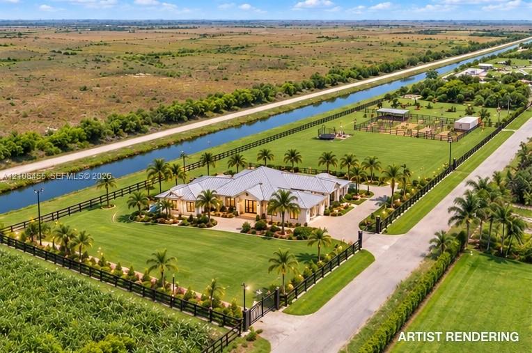 Aerial perspective of an expansive estate featuring a metal roof structure, paved circular driveway, perimeter fencing, mature palm landscaping, and extensive manicured grounds