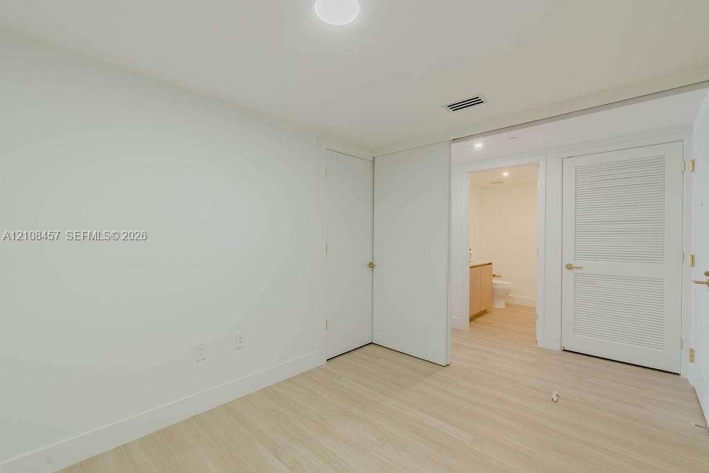Interior space featuring wood-finish flooring, a louvered closet door, a flush-mount ceiling light fixture, and a neutral color palette
