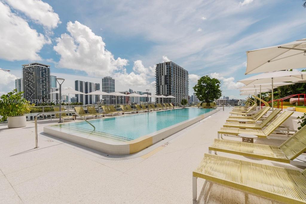 Rooftop swimming pool featuring a rectangular basin, light-colored hardscaping, integrated safety railing, and metal handrails