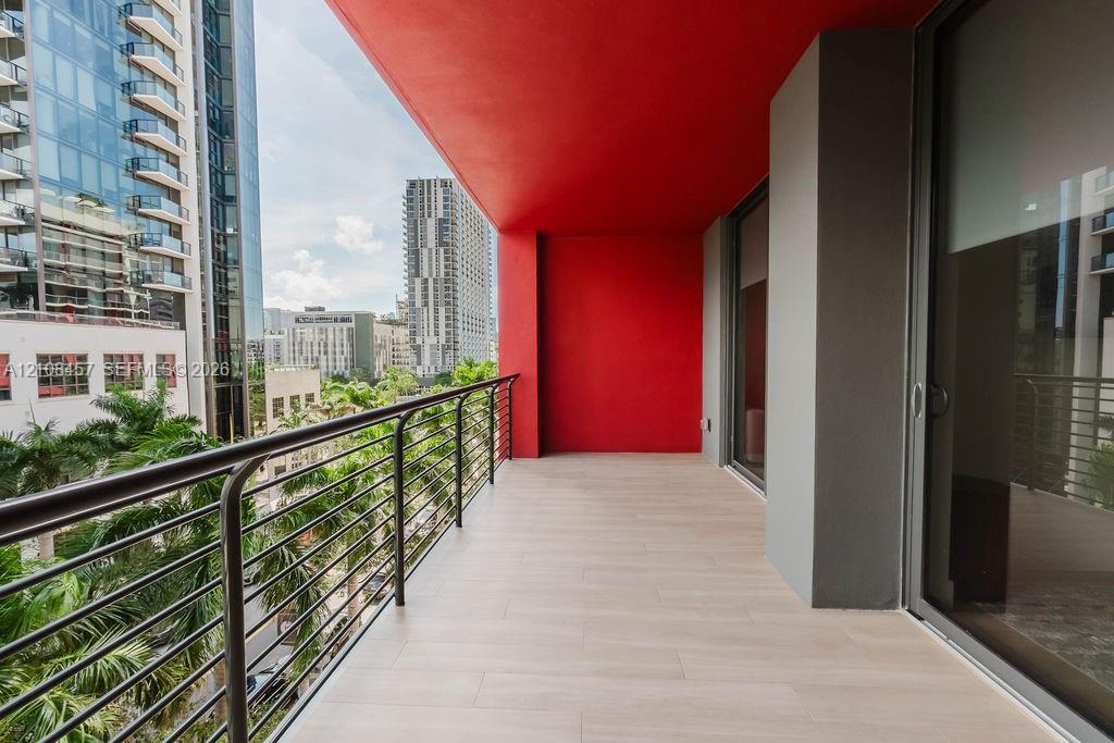 Covered balcony featuring wood-finish tile flooring, metal railing, and high-contrast red ceiling accent