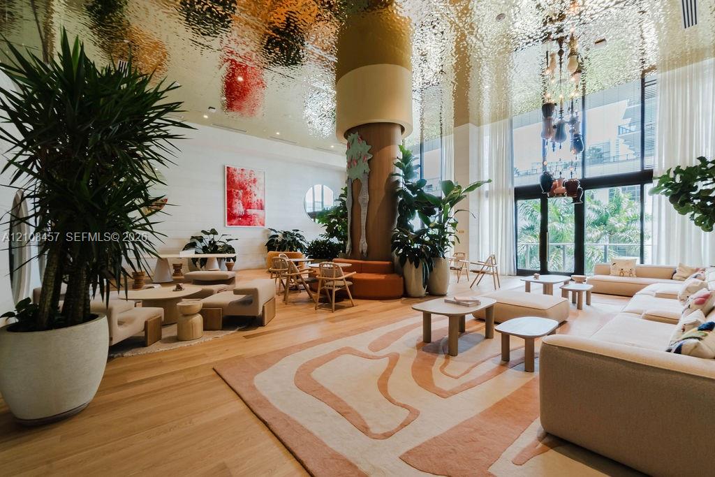 Common area featuring a textured gold-finish ceiling, floor-to-ceiling windows, wide-plank wood flooring, and a central architectural pillar
