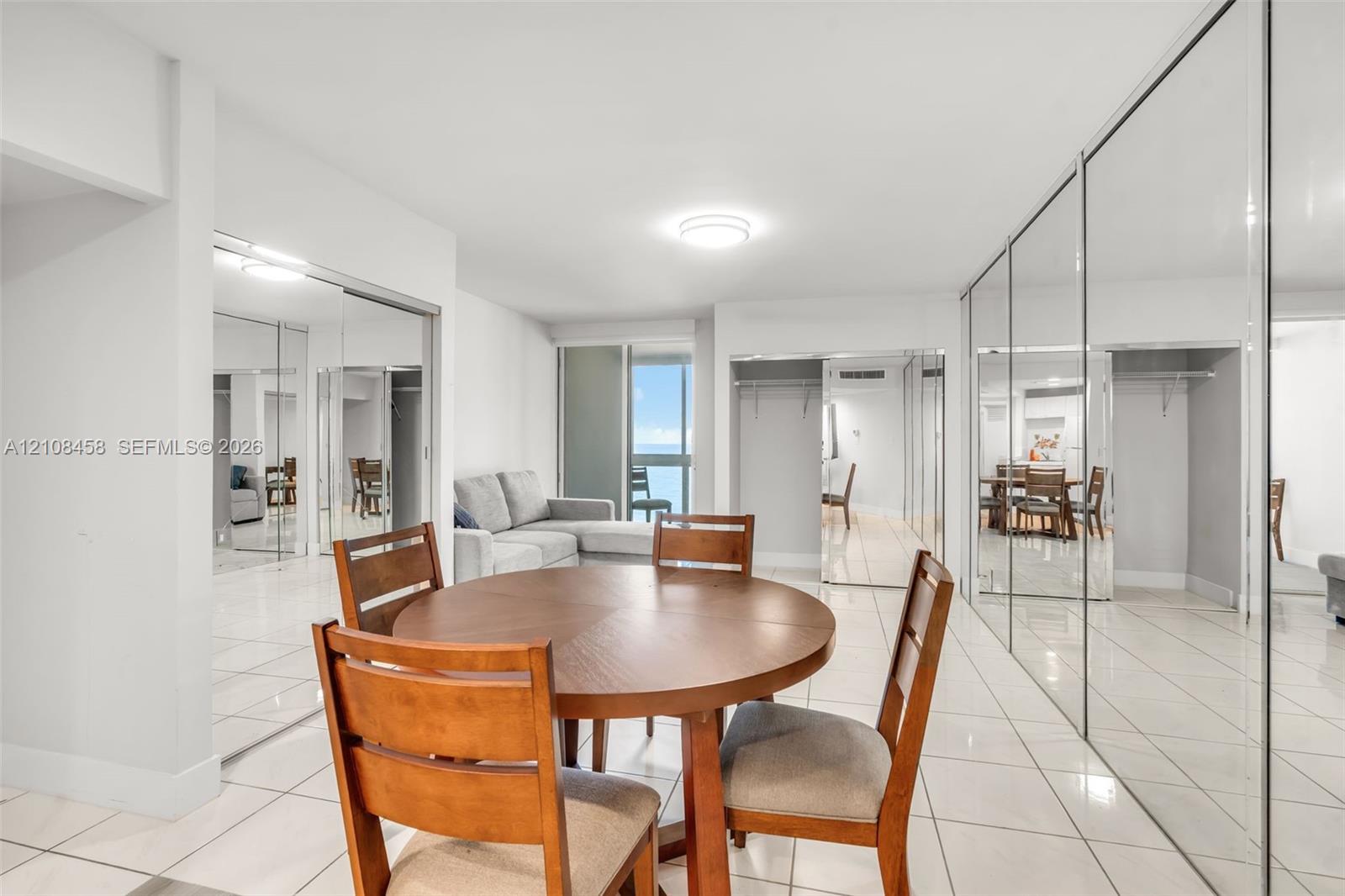 Expansive living area featuring reflective floor-to-ceiling mirrored closet doors, polished tile flooring, and a sliding glass door providing external natural light