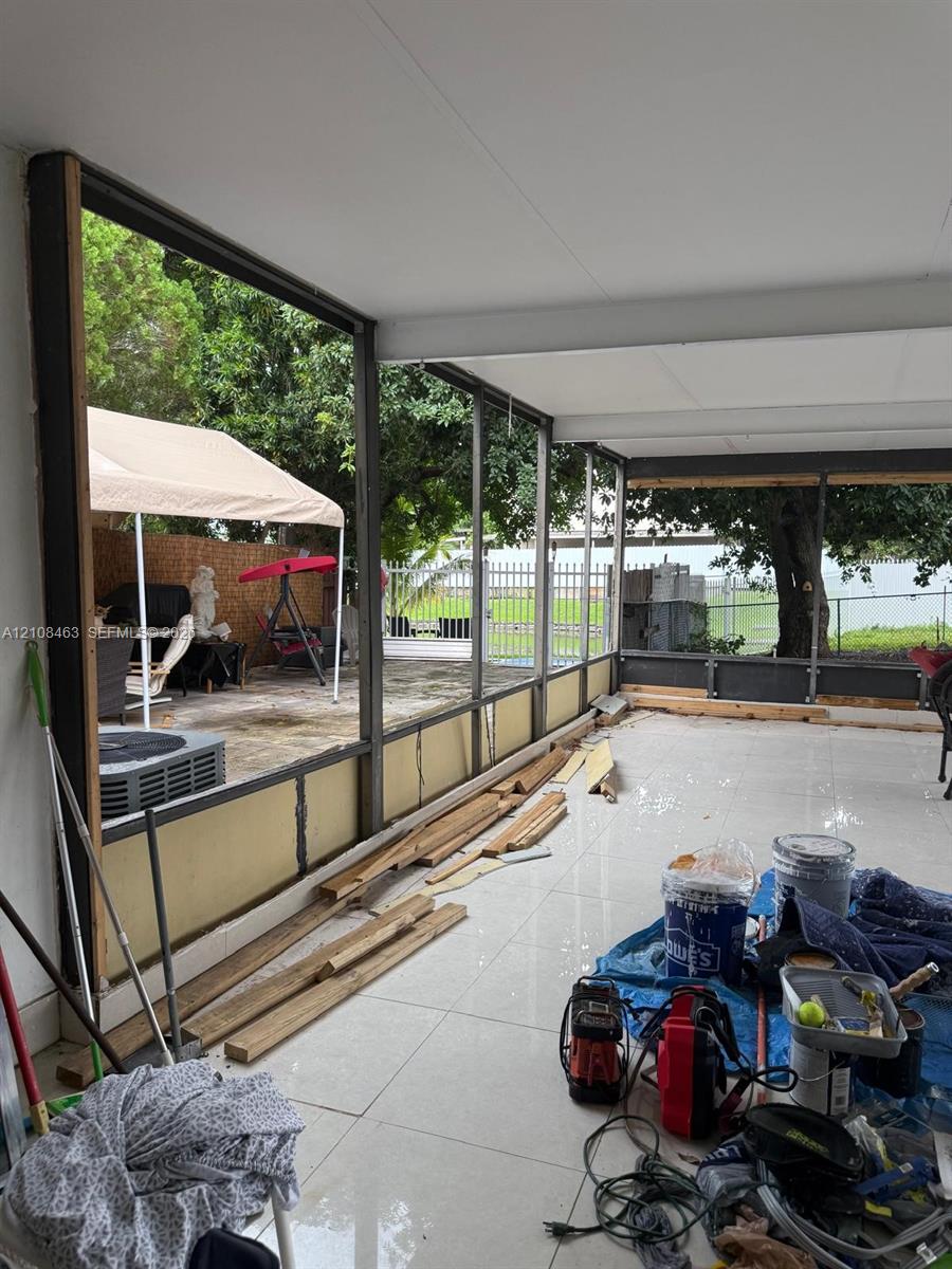 Enclosed porch featuring large-format ceramic tile flooring, a solid panel ceiling, and extensive metal-frame screening