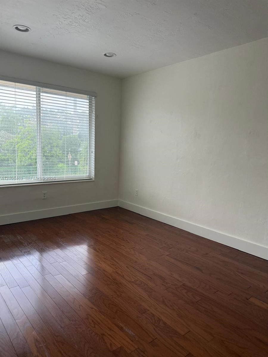 Room featuring wood-finish flooring, recessed lighting, and a window with horizontal blinds