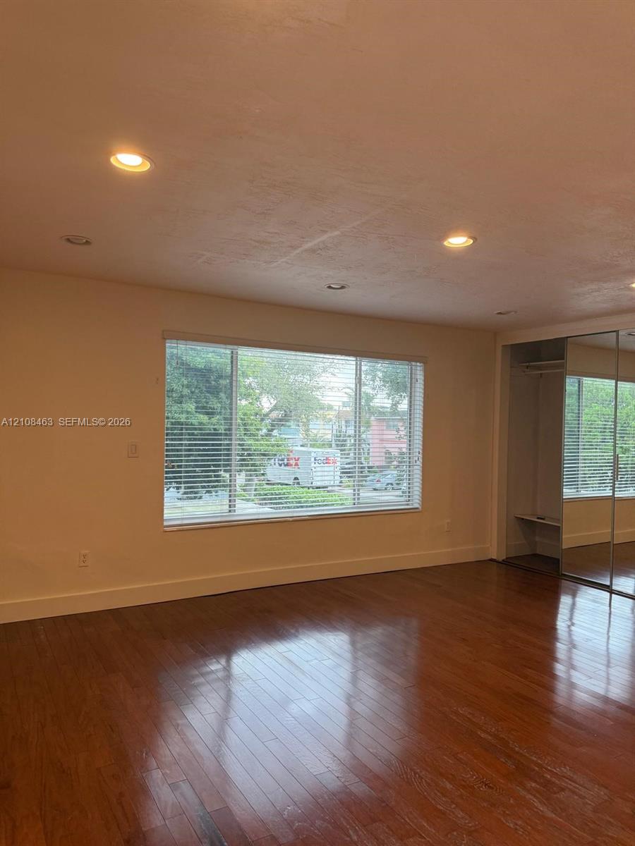 Wood-finish flooring, recessed ceiling lighting, and built-in closet with mirrored sliding doors