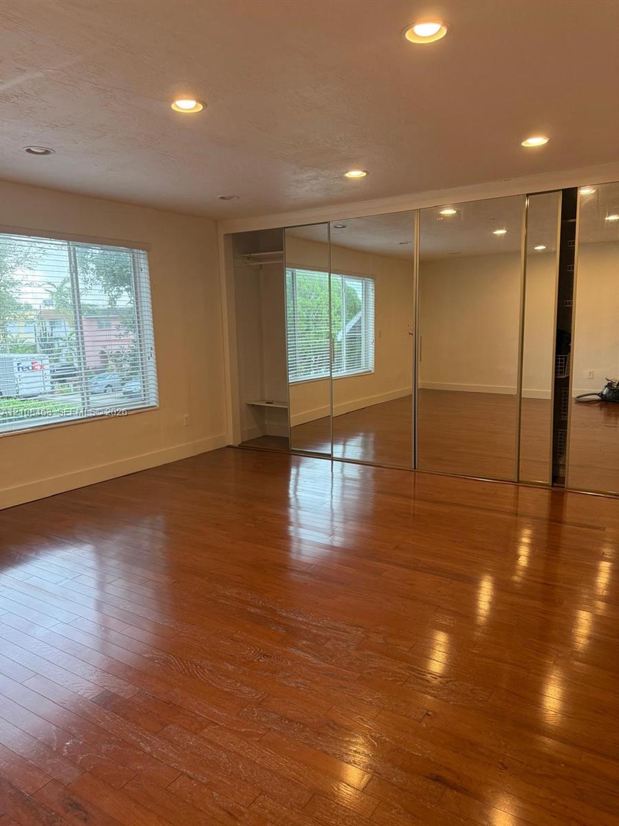 Room featuring wood-finish flooring, recessed lighting, and wall-to-wall mirrored closet doors