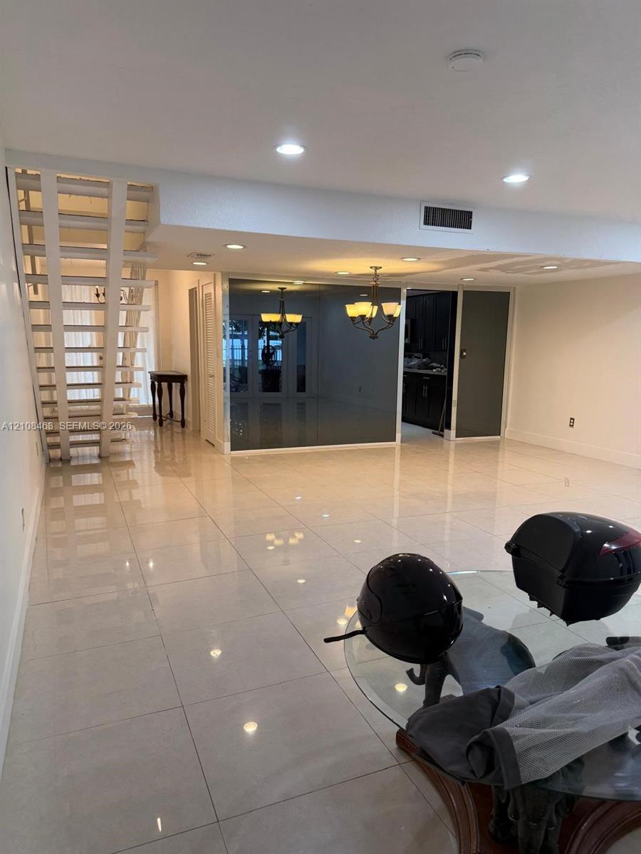 Large-format tile flooring, open staircase with white-finish metal railings, recessed ceiling lighting, and mirrored wall accents Large-format tile flooring, open staircase with white-finish metal railings, recessed ceiling lighting, and mirrored wall accents