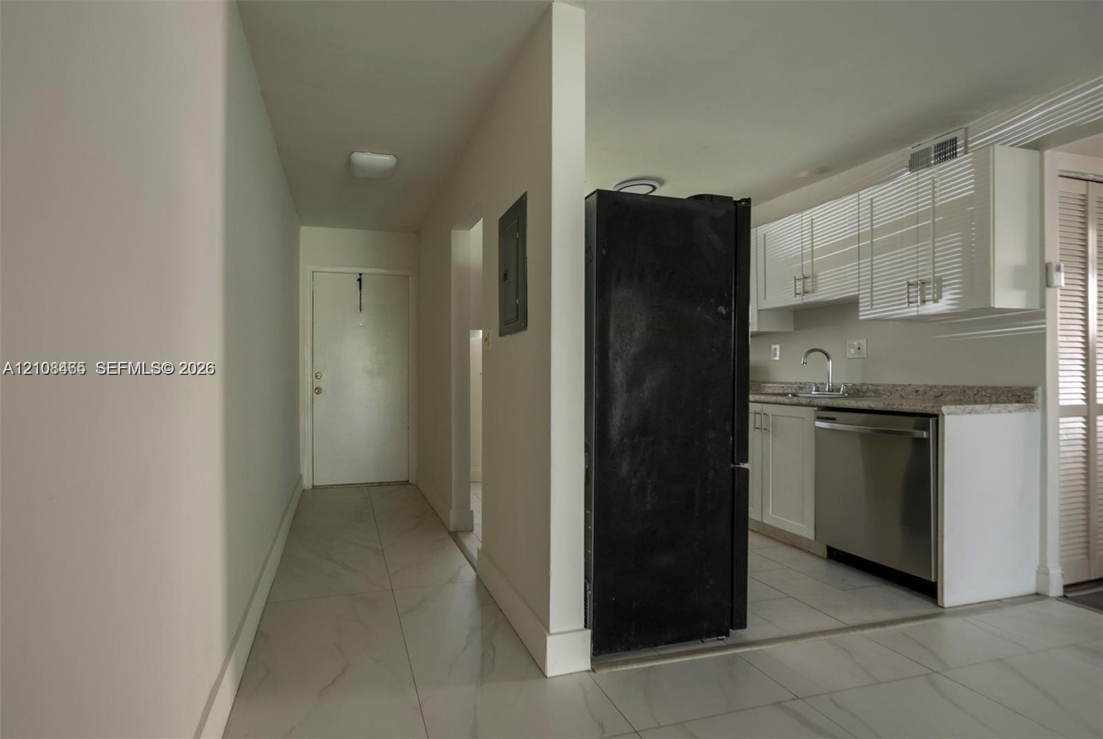 Kitchen featuring white cabinetry, stone-finish countertops, stainless steel dishwasher, and large-format tile flooring