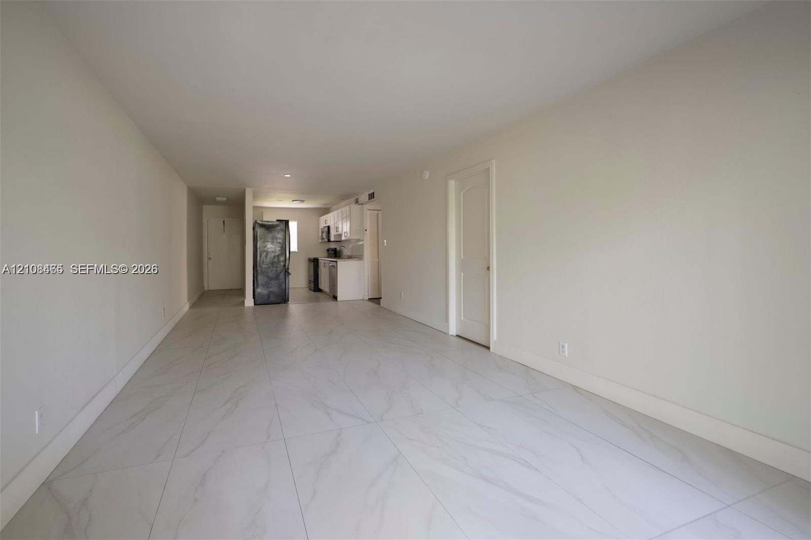 Large format light-toned tile flooring throughout an open floor plan with white cabinetry and finished interior doors