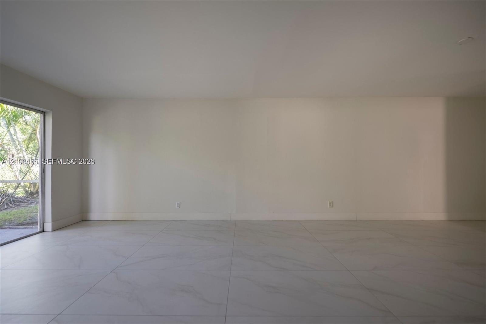 Large-format tile flooring, neutral wall tones, and glass sliding door providing outdoor access
