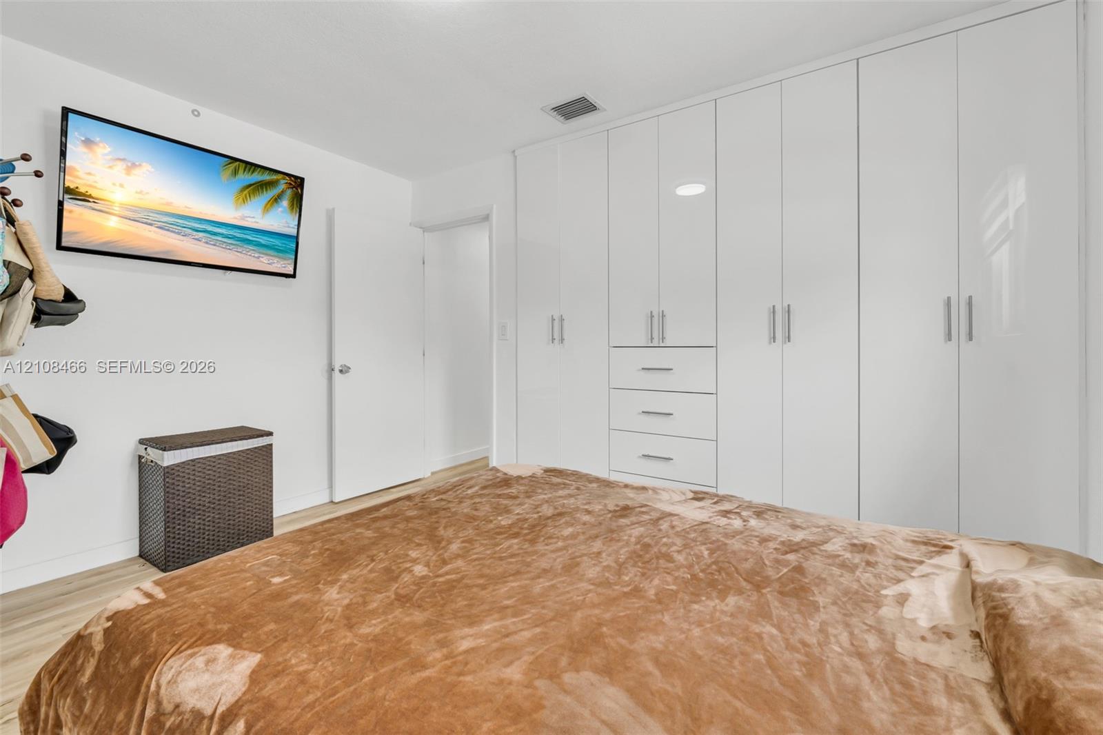 Floor-to-ceiling white cabinetry featuring integrated drawer storage, sleek vertical hardware, and wood-finish flooring