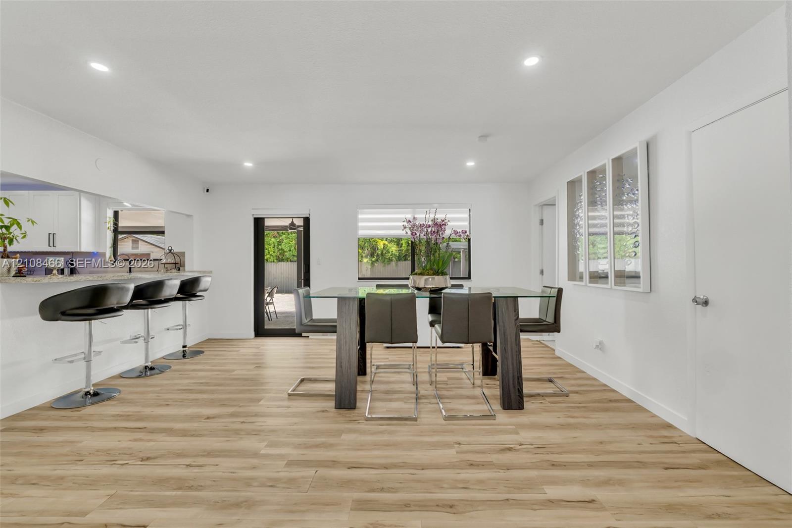Open floor plan featuring wood-finish flooring, recessed lighting, and a kitchen breakfast bar with stone-surfaced countertop Open floor plan featuring wood-finish flooring, recessed lighting, and a kitchen breakfast bar with stone-surfaced countertop