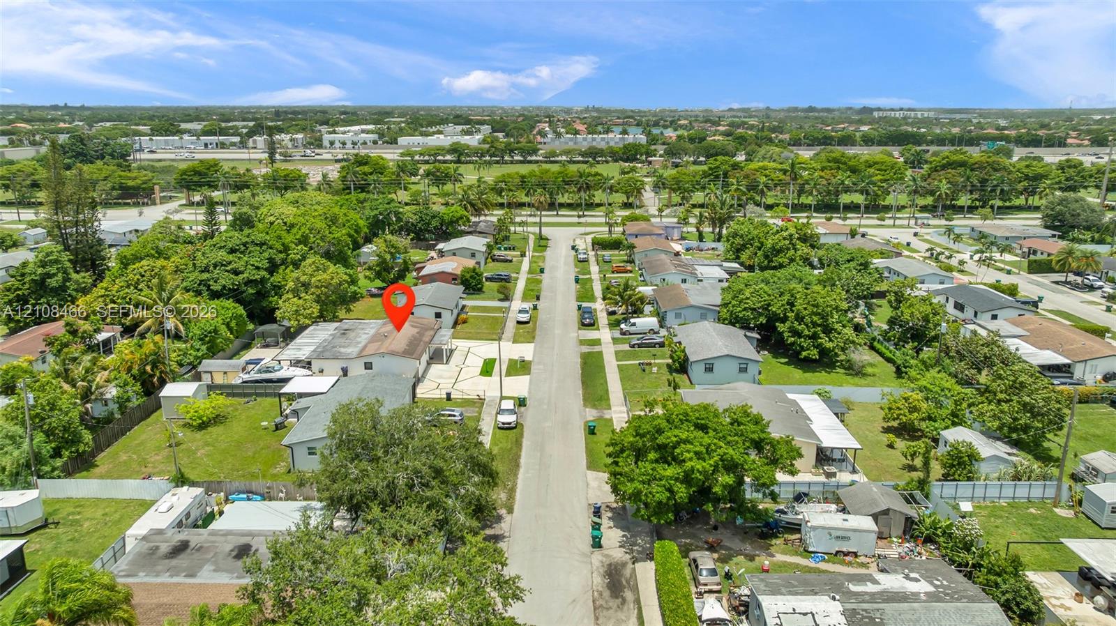 Aerial perspective of a residential property featuring a paved driveway, a spacious backyard, and mature surrounding landscaping