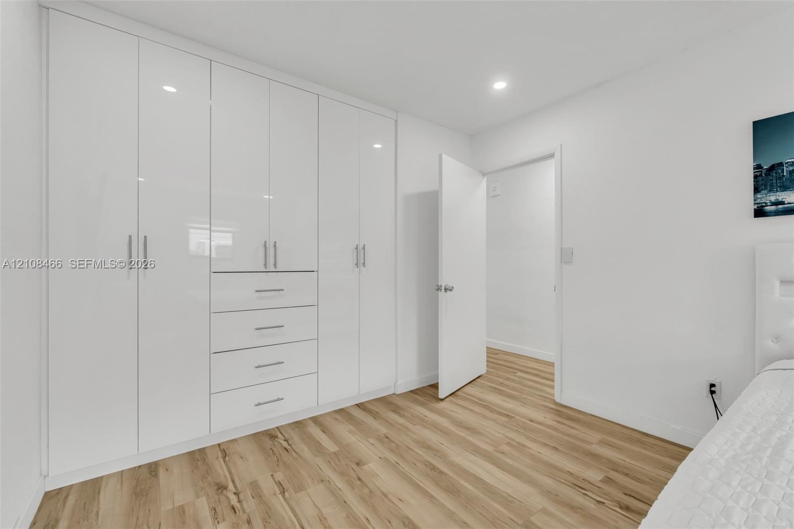 Built-in floor-to-ceiling cabinetry with white high-gloss finish, integrated drawers, brushed metal hardware, and wood-finish flooring