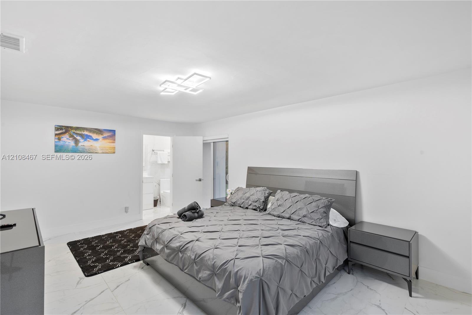 Neutral-toned interior featuring large-format tile flooring and a modern multi-tiered geometric flush-mount light fixture