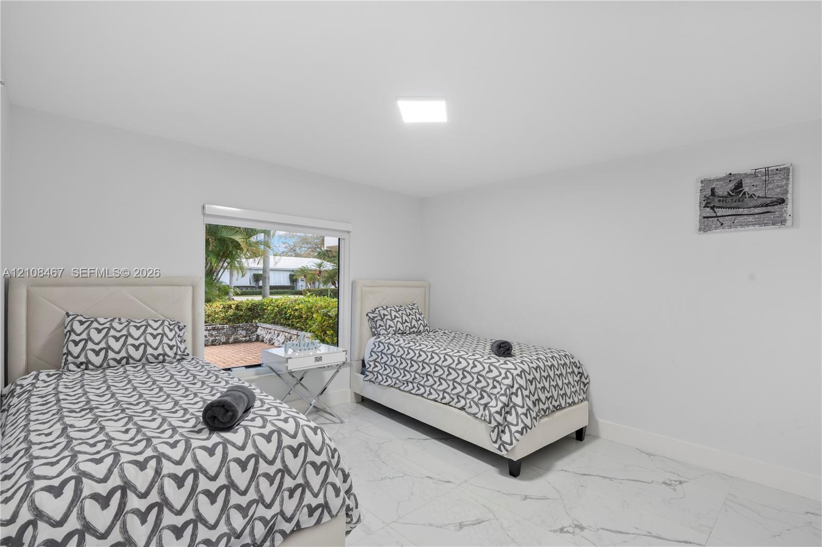 Neutral-toned room featuring large-format tile flooring and a rectangular window with exterior greenery