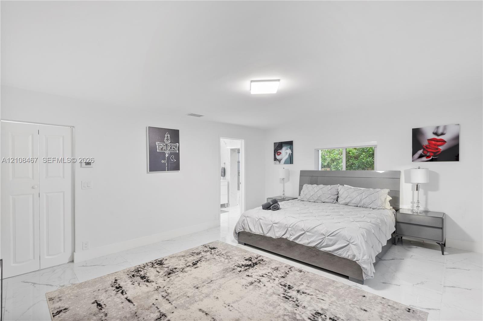 Polished stone-finish flooring, crisp white interior walls, flush-mount ceiling lighting, and a double-door closet with recessed paneling
