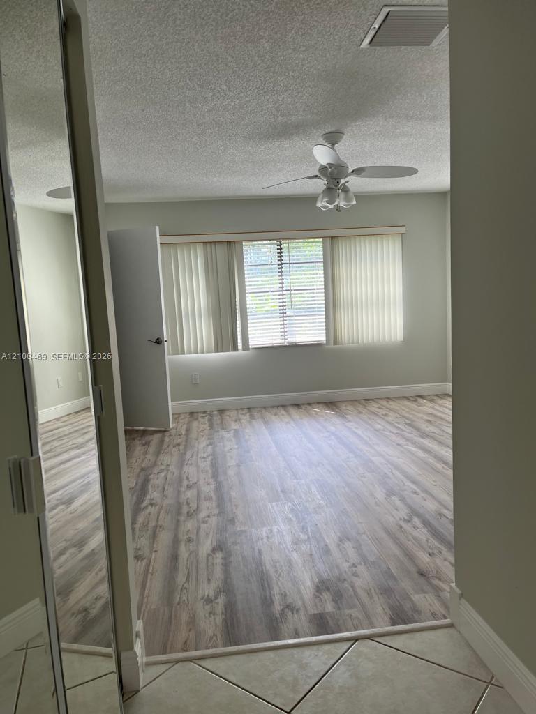 Room featuring wood-finish flooring, a ceiling fan with integrated lighting, and mirrored closet doors.