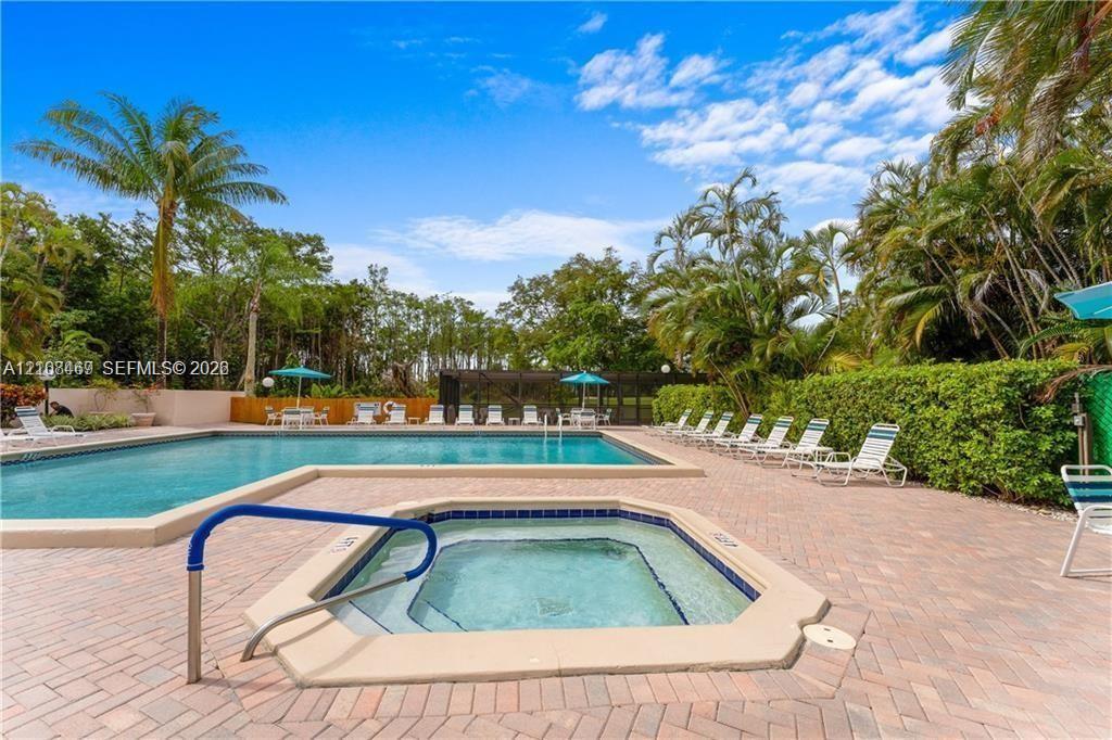 In-ground swimming pool and attached spa featuring a brick-paver pool deck, perimeter landscaping, and privacy fencing.