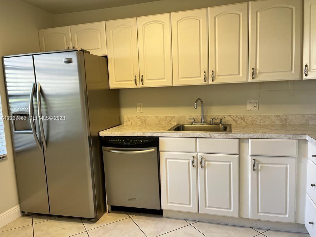 Kitchen featuring white shaker-style cabinetry, neutral patterned countertops, stainless steel appliances which includes side-by-side refrigerator, dishwasher, electric range and microwave-hood