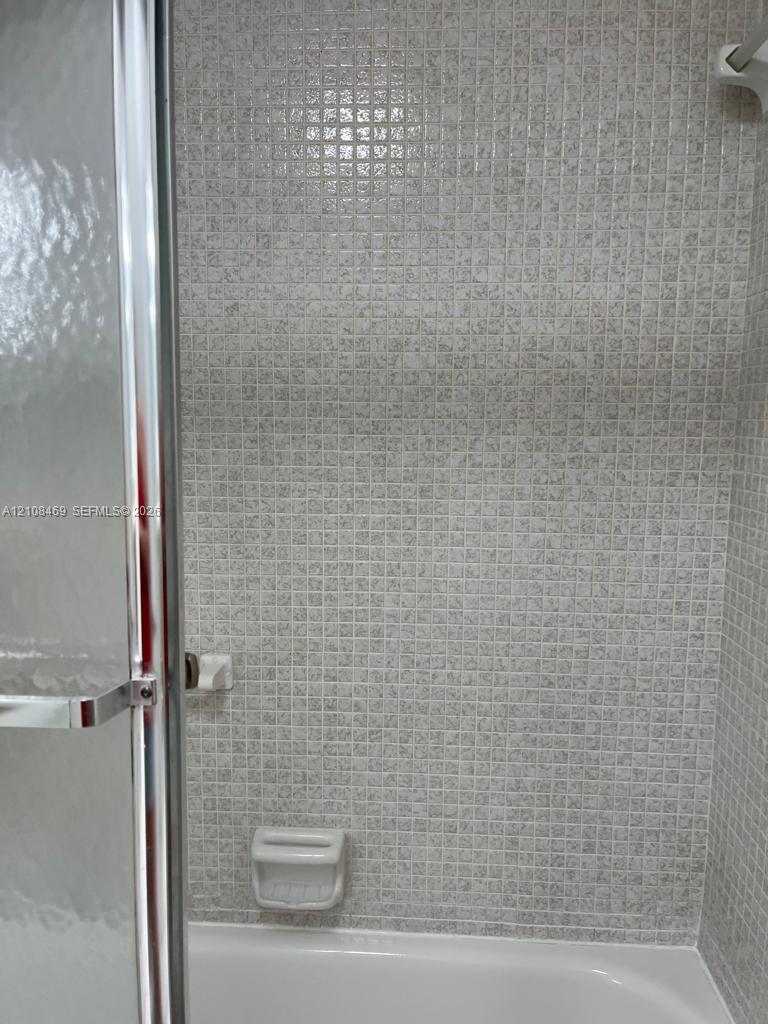 Bath with Tub, featuring small-format mosaic wall tiling, a built-in soap dish, and a enclosure framed glass door