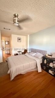 Wood-finish flooring, textured ceiling, and a modern brushed-nickel ceiling fan with integrated lighting