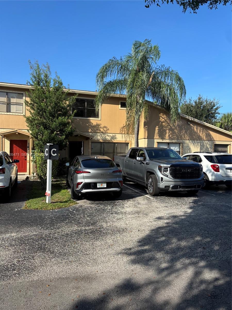 Stucco exterior facade with dedicated off-street parking, mature palm tree landscaping, and multi-paned windows