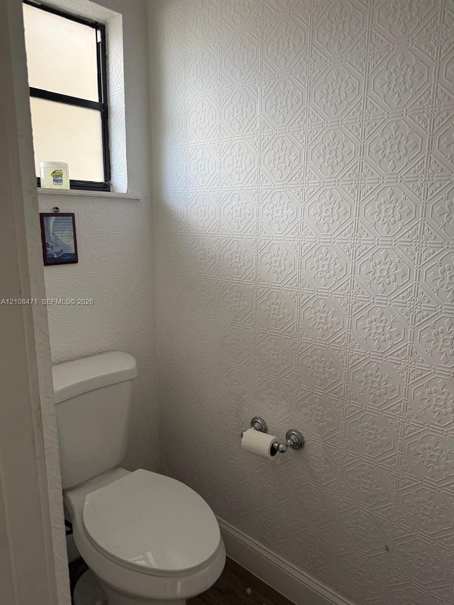 Textured wall treatment featuring a repeating geometric pattern, porcelain toilet, and a window with a black frame