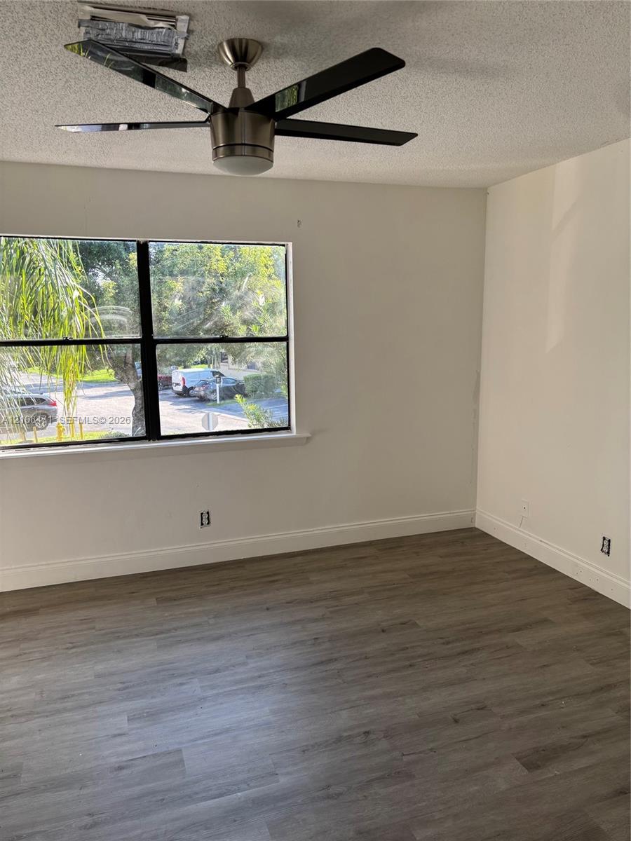 Wood-finish flooring, multi-pane window with black framing, and modern ceiling fan with integrated light fixture