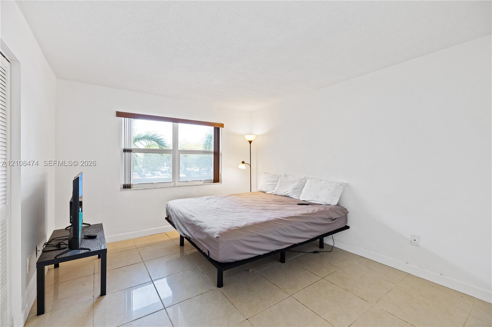 Neutral-toned tile flooring, white wall finishes, and a window with horizontal blinds