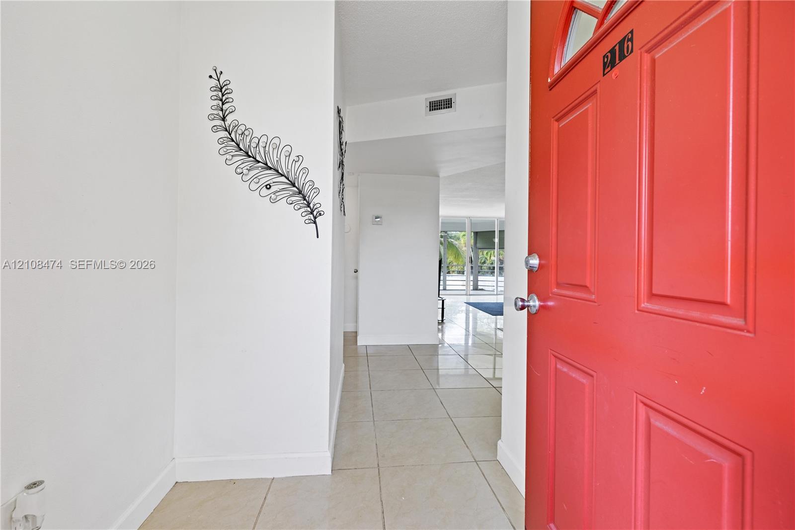 Entryway featuring a solid-panel door with arched glass inlay, neutral-toned tile flooring, and clean-finish walls