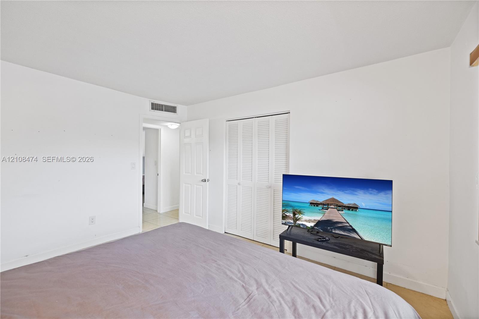 Neutral interior room featuring white walls, a white bi-fold louvered closet door, and a white interior swing door