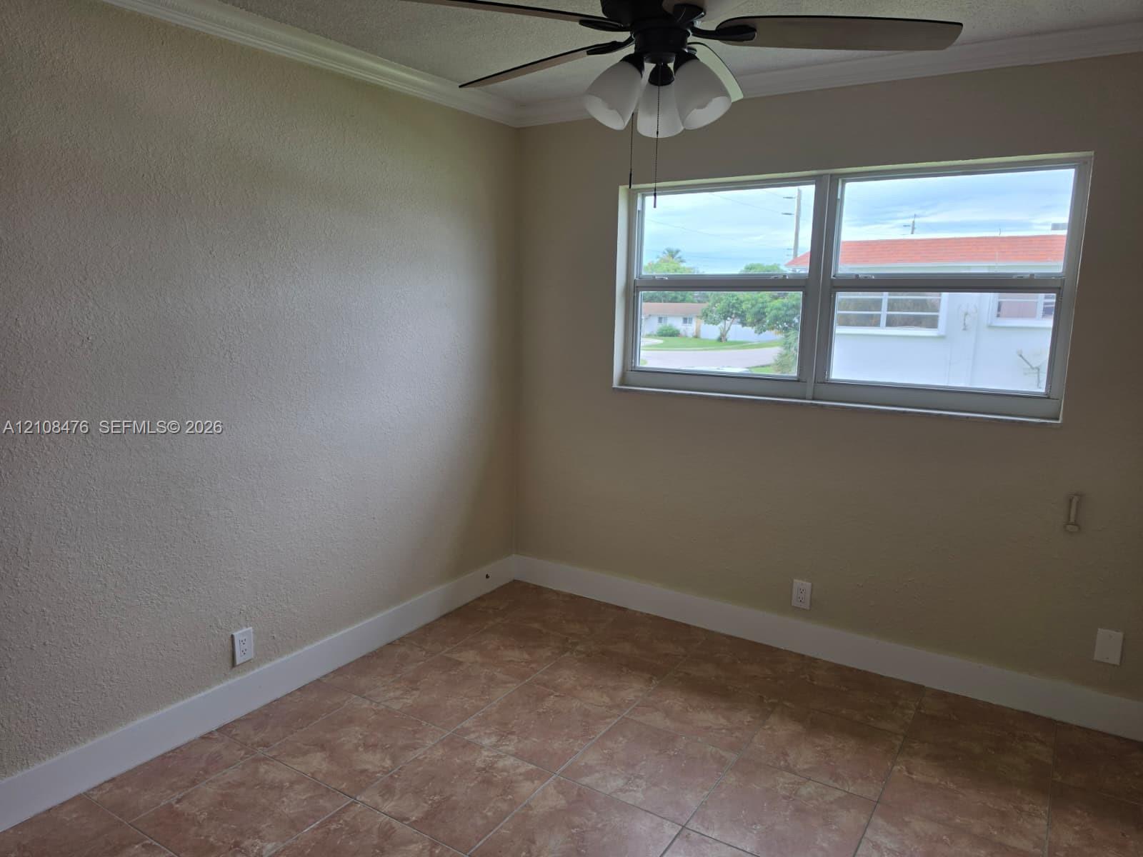 Room featuring neutral-toned walls, tile flooring, crown molding, and a multi-light ceiling fan