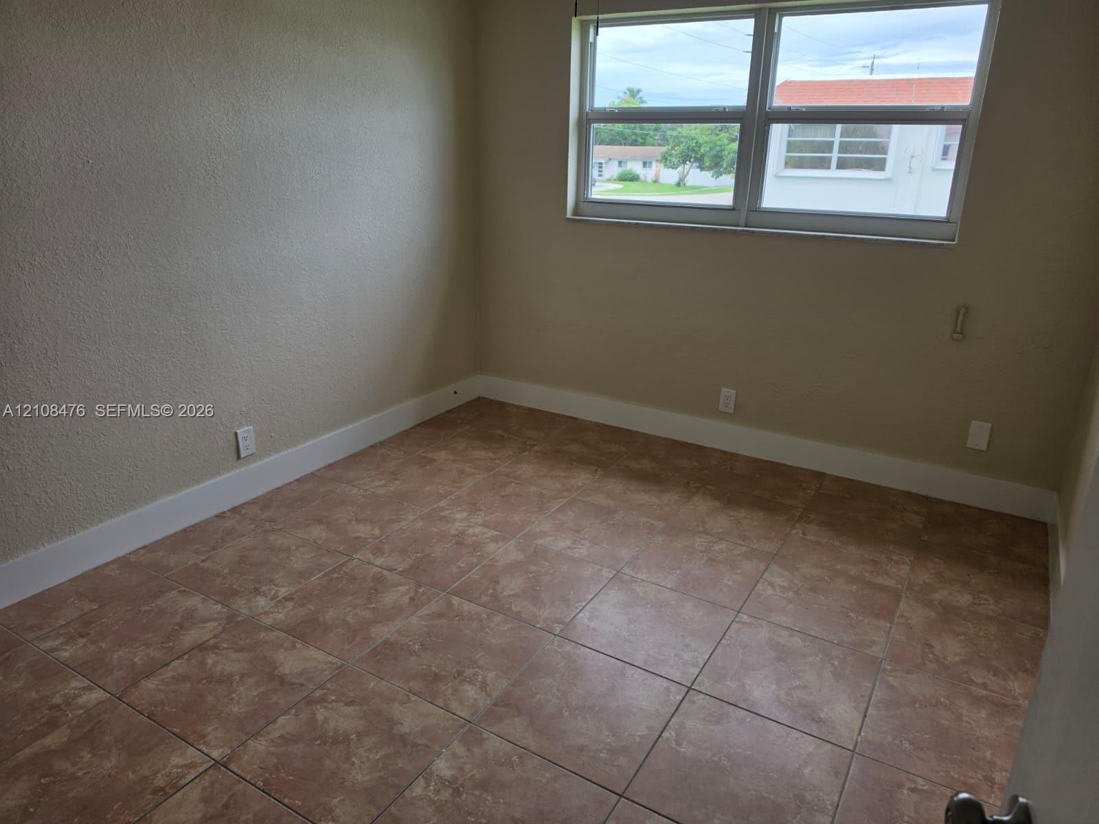 Neutral-toned interior space featuring large-format tile flooring and a multi-pane window