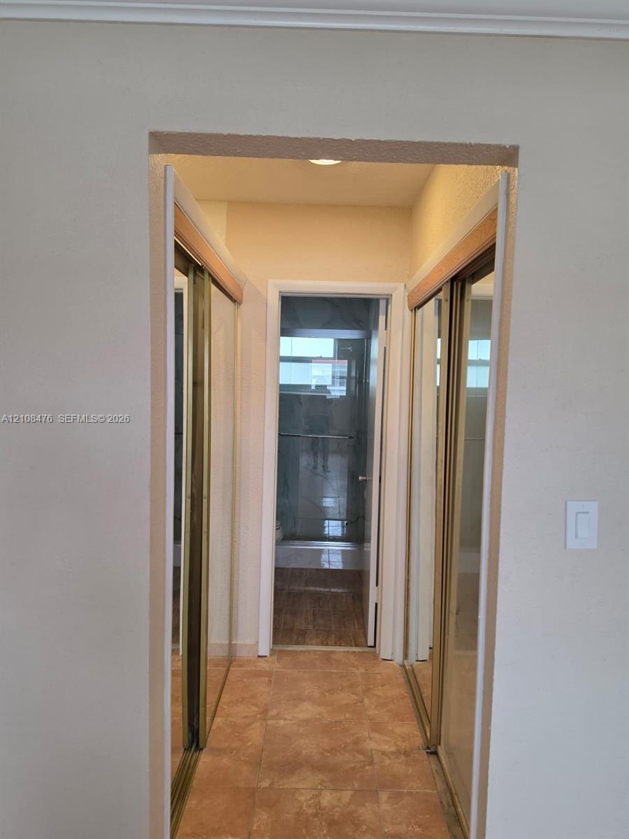 Dual sliding mirrored closet doors with gold-tone frames and tile flooring