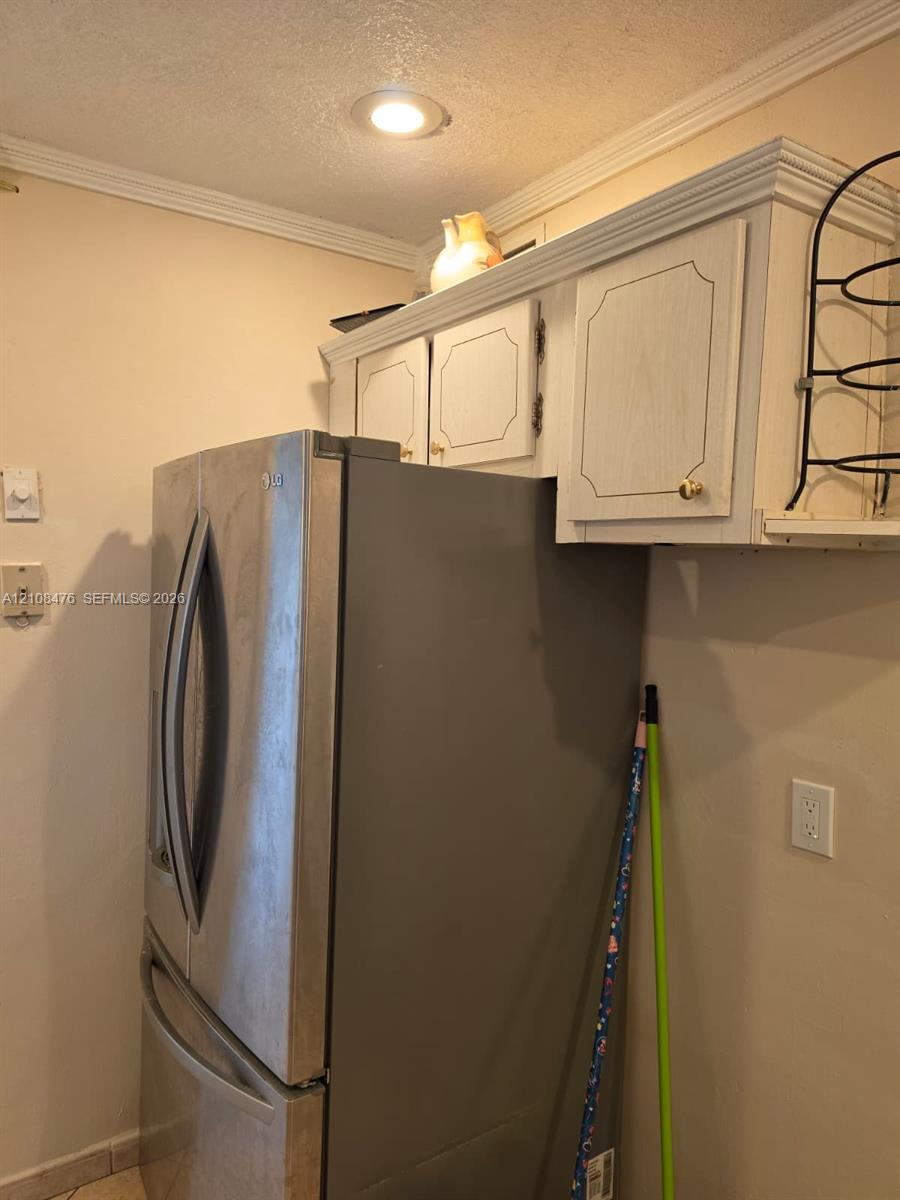 Stainless steel french-door refrigerator, custom-painted cabinetry with crown molding, and recessed ceiling lighting Stainless steel french-door refrigerator, custom-painted cabinetry with crown molding, and recessed ceiling lighting